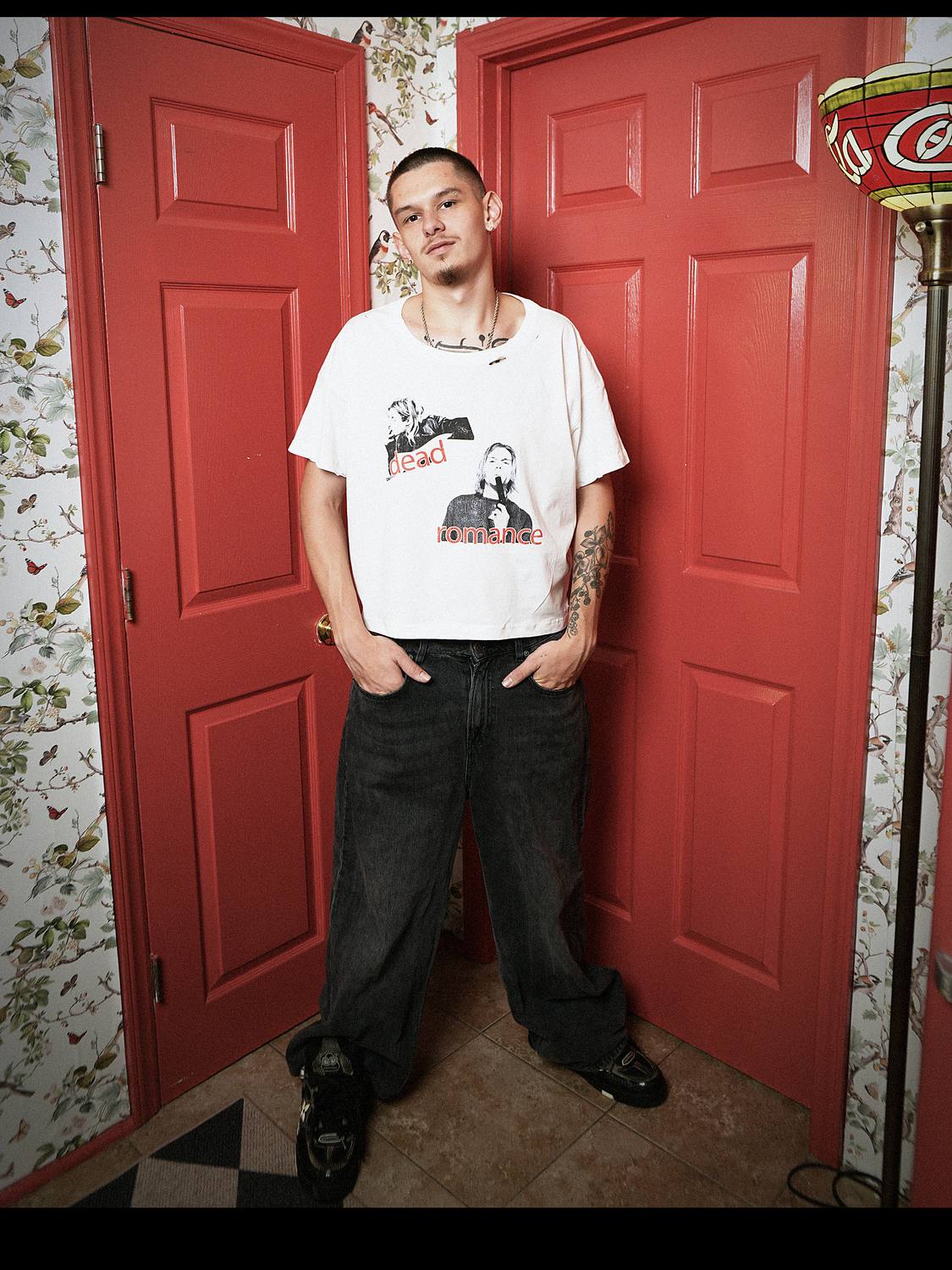 Model wearing the kurt cobain white tee, standing between red panel doors